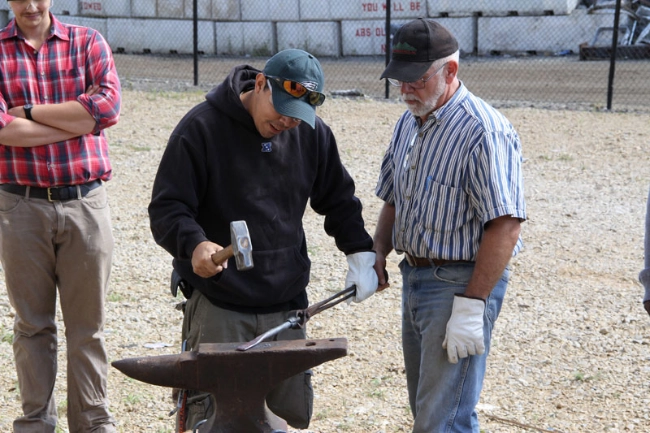 Two men hammering a tool