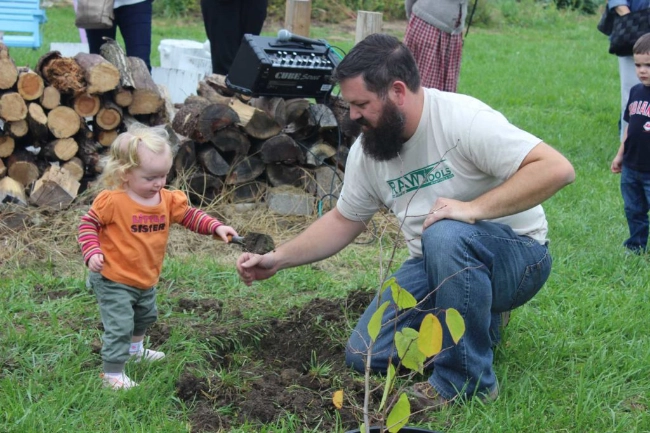 Mike Martin helping a little girl dig in the dirt